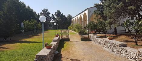 A courtyard with a gravel path, stone walls, and potted plants.