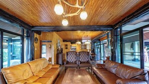 A spacious living room with leather sofas, a wooden coffee table, and a chandelier. - Khaoyai Valley 4 (Pak Chong)