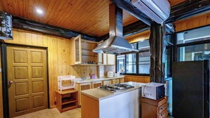 A kitchen with wooden cabinets, a gas stove, a microwave, and a refrigerator. - Khaoyai Valley 4 (Pak Chong)