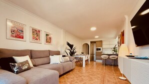 Una sala de estar moderna con un sofá seccional gris, un comedor y una cocina al fondo.