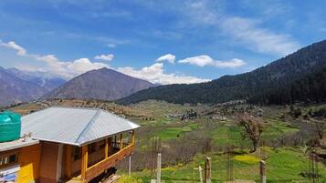 A mountain view with a wooden building and a green field.