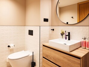 Ein modernes Badezimmer mit Toilette, Waschbecken und Spiegel.