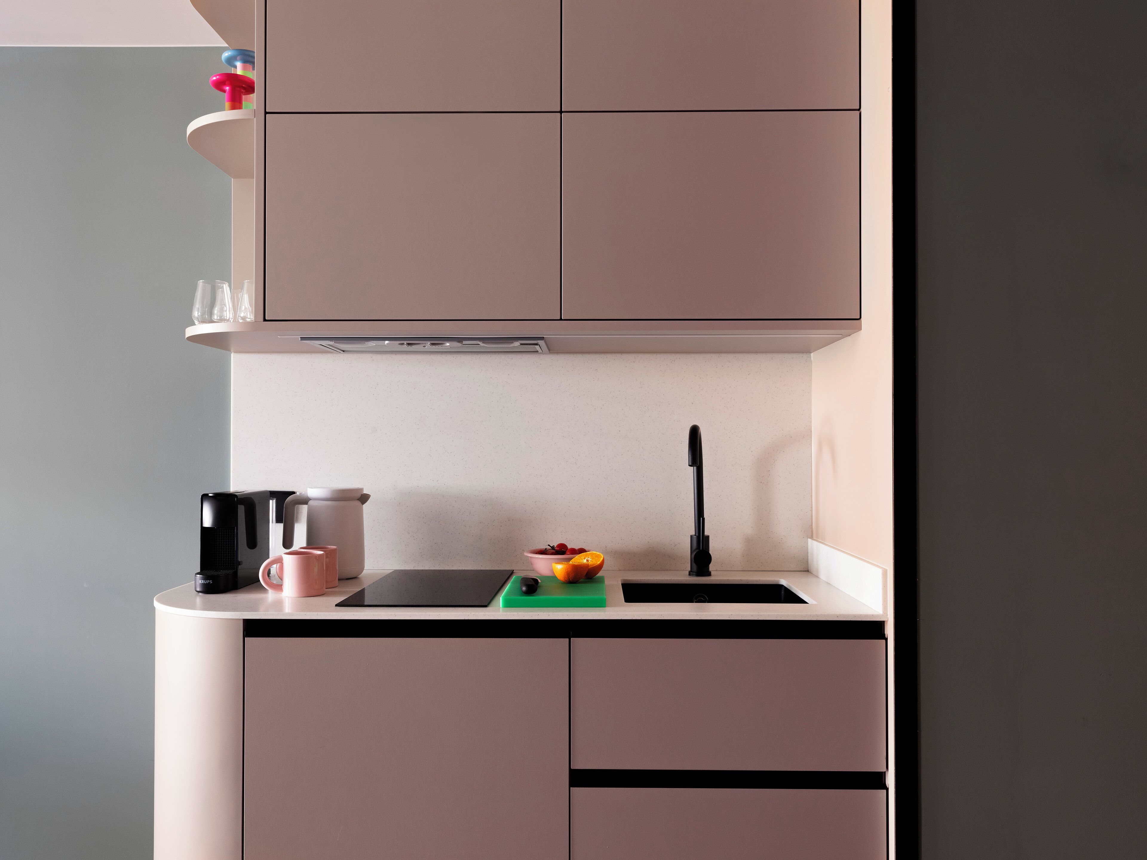 A modern kitchen with a black countertop, a sink, and a range hood.