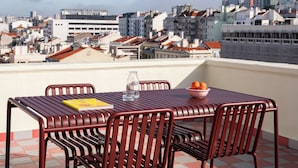 A rooftop terrace with a table and chairs, a bowl of fruit, and a glass of water. - Numa Lisbon Anjos (Lisbon)