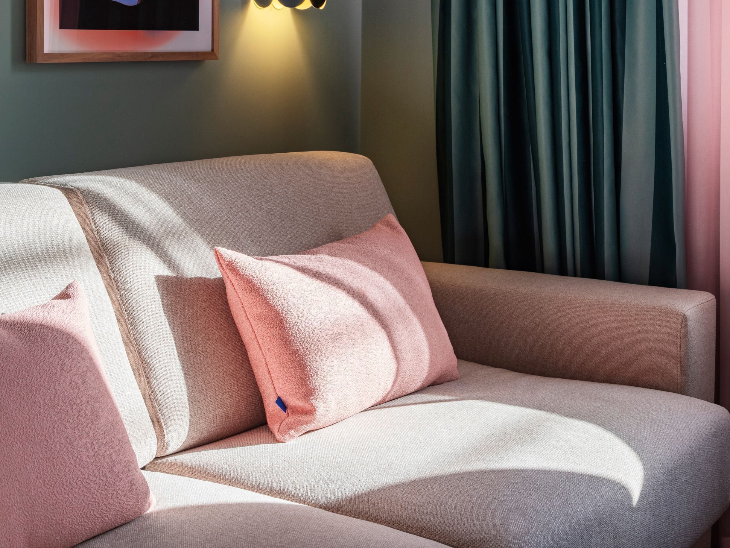 Un sofá con tela texturizada y una almohada rosa.