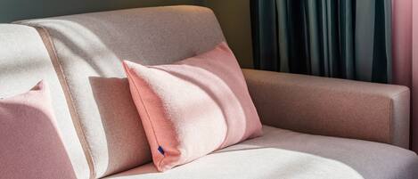 Un sofá con tela texturizada y una almohada rosa.