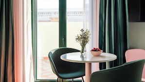 A room with a round table, two chairs, a vase with flowers, and a bowl of fruit. - Numa Lisbon Anjos (Lisbon)