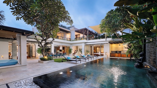 A modern pool area with lounge chairs and a waterfall feature.