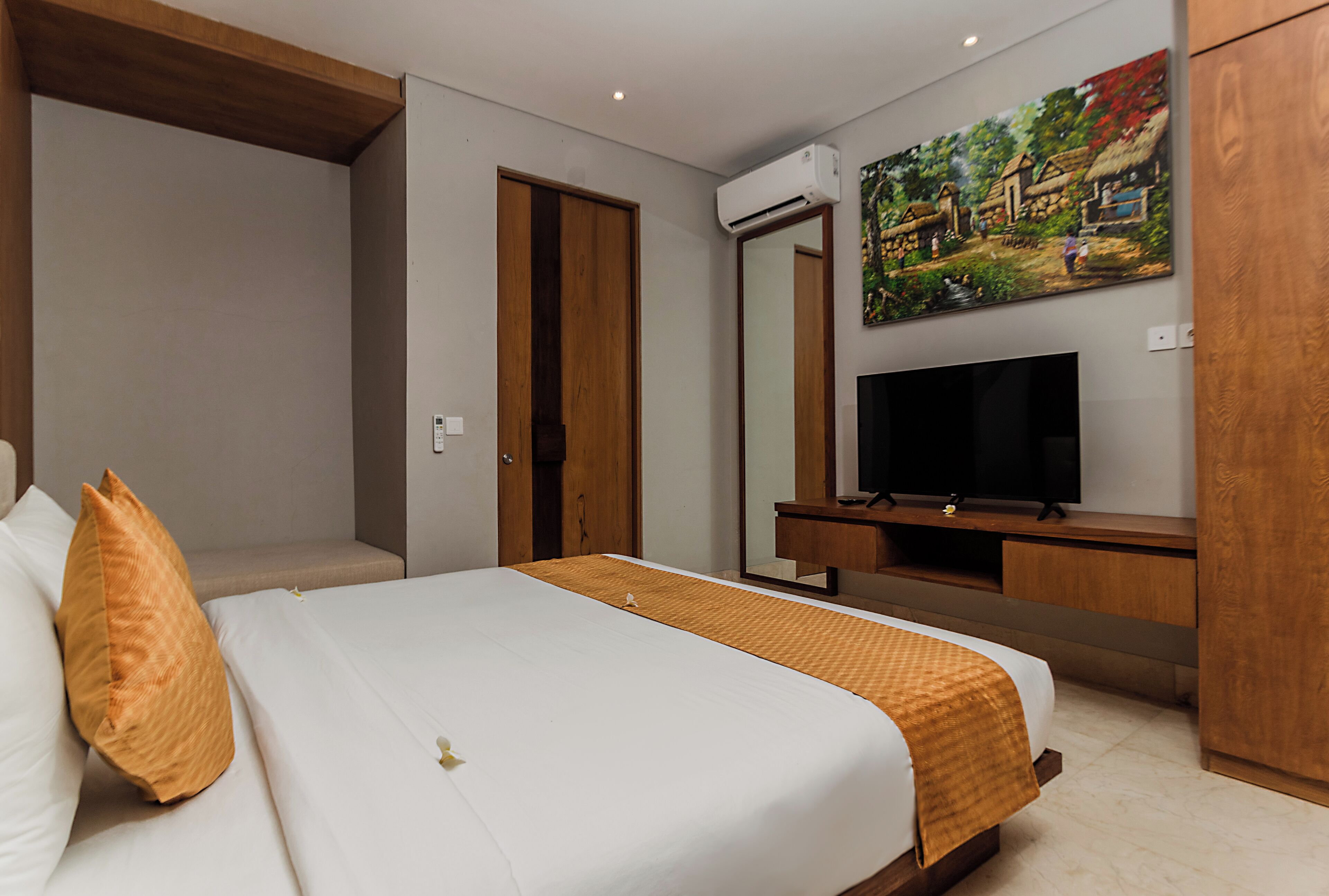 A hotel room with a bed, a TV, a painting, and a wardrobe.