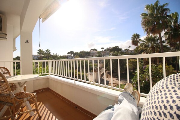 A balcony with a white railing, a table, and chairs.