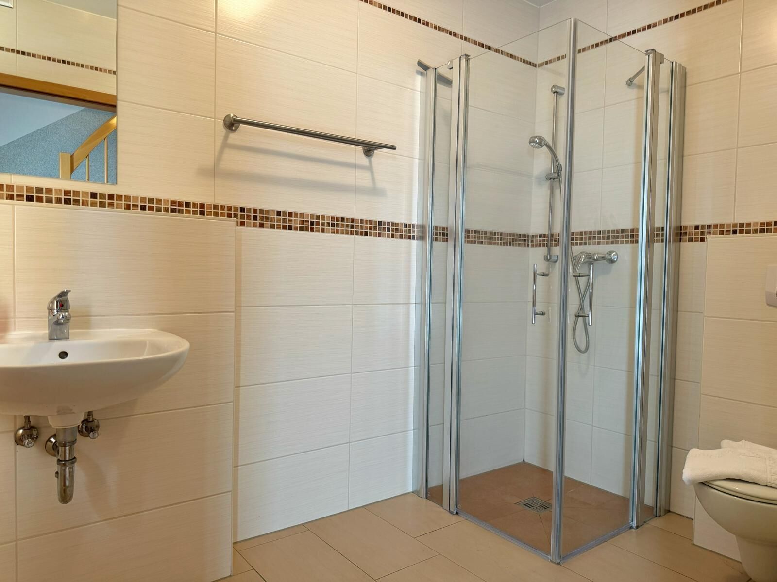 Et moderne badeværelse med bruseniche, vask og toilet.
