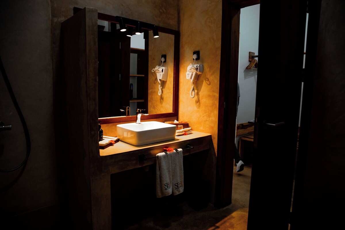 Un baño con un espejo grande, un lavabo, un teléfono y un perchero para toallas.