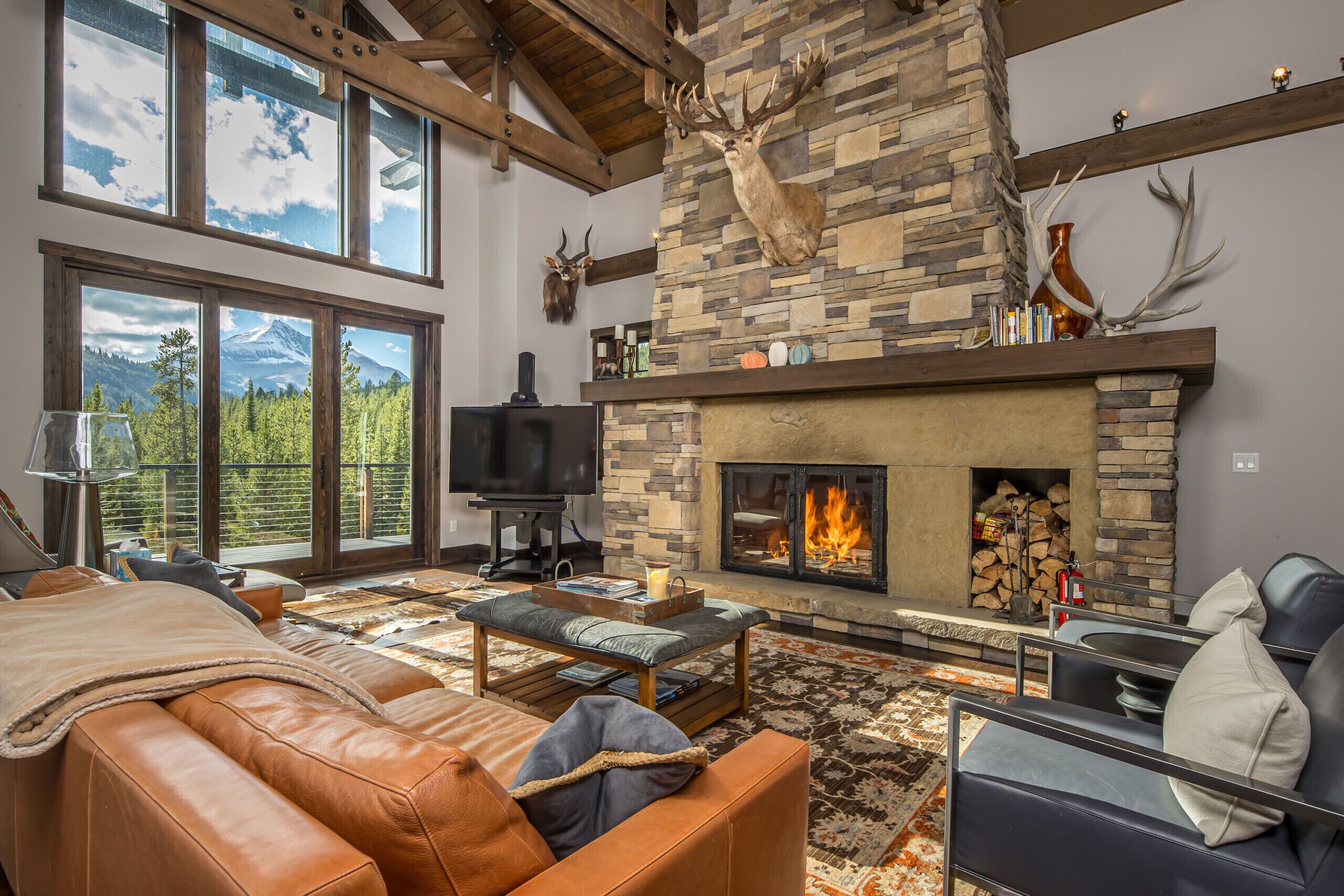Una sala de estar amplia con chimenea de piedra, sofás de cuero y un televisor grande.