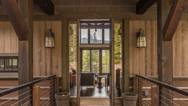 L’entrée d’un chalet en bois, dotée d’une porte vitrée qui donne sur un patio extérieur.