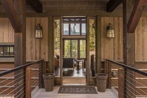 Een houten chalet-ingang met een glazen deur die leidt naar een terras.