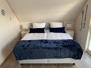 Relax in a spacious bedroom with a large bed, sloped ceiling, and wooden beams.