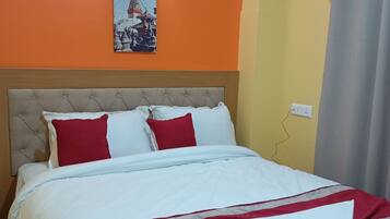 Una habitación de hotel con una cama, una lámpara fijada a la pared y un cuadro de un templo.