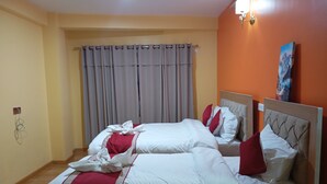 Uma cama de casal com roupa de cama branca e vermelha, uma cortina cinza e um quadro na parede.