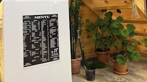 Een houten interieur met een witte koelkast waarop een menukaart staat.