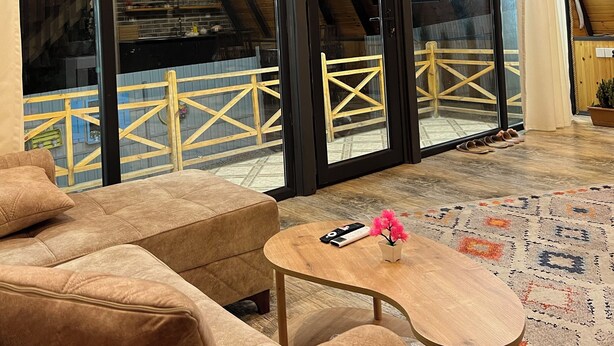 Een ruime kamer met een hoge plafond, grote ramen en uitzicht op een balkon.