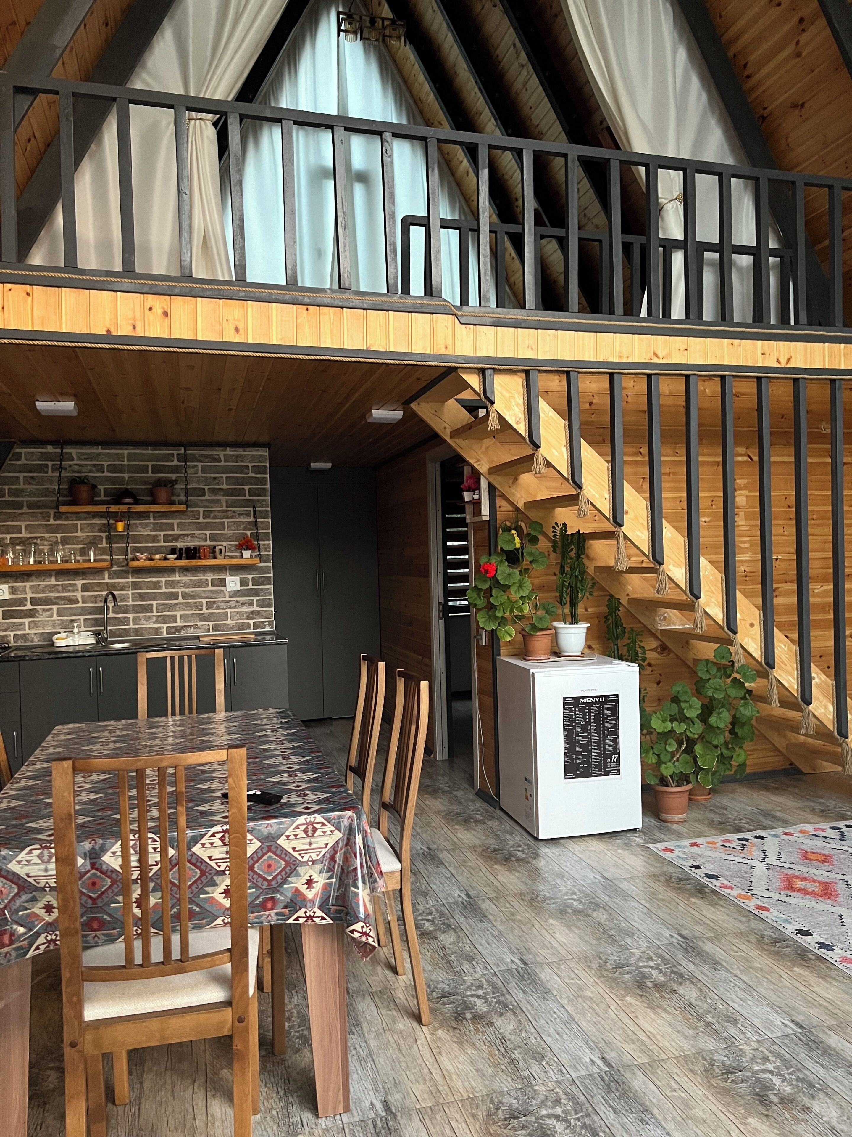 A loft-style room with a dining area, kitchen, and a staircase.