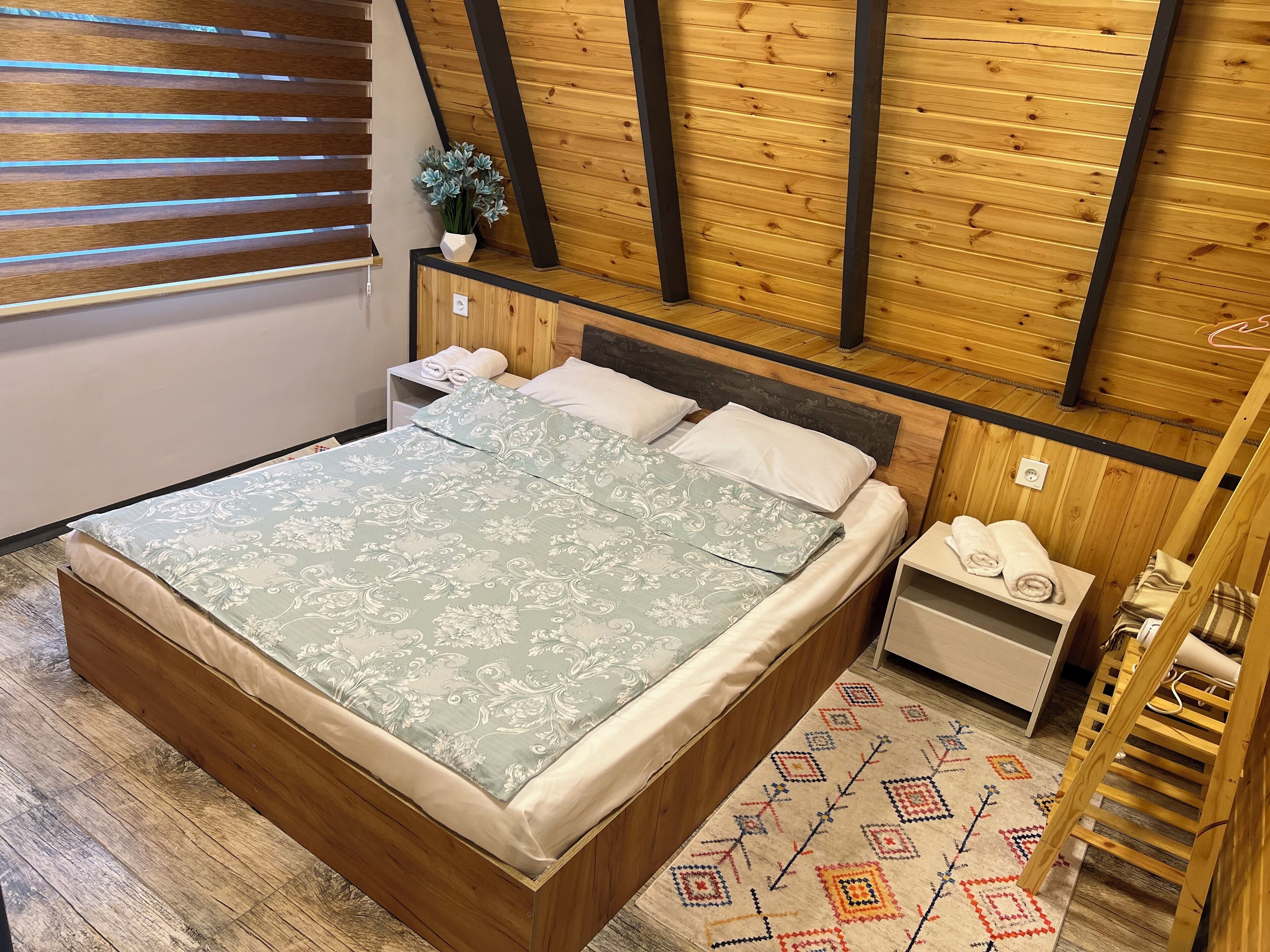 Una stanza con pannelli in legno, un letto, comodini e una piccola pianta.