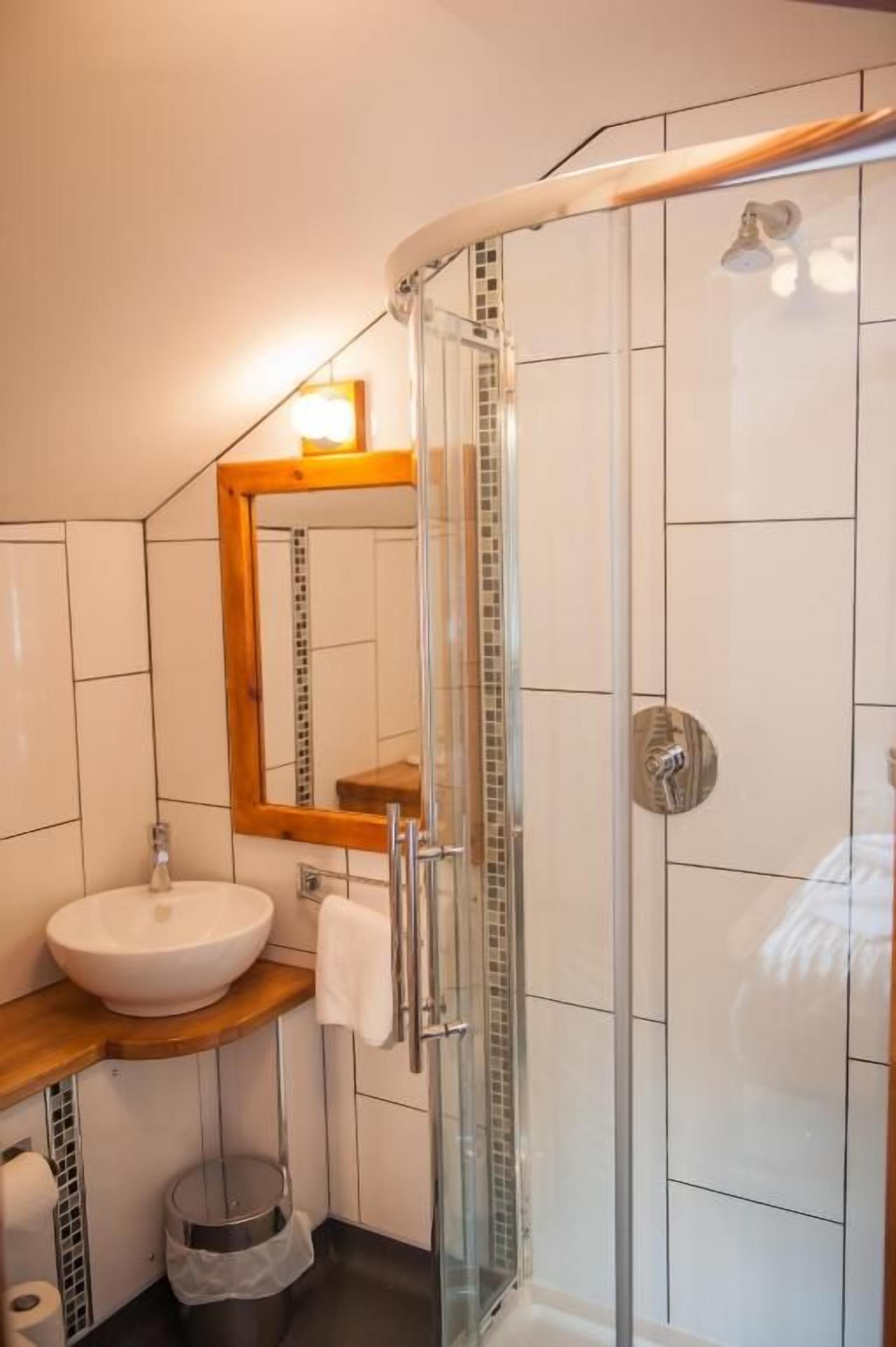 Un baño con cabina de ducha de vidrio, un lavamanos con encimera de madera y un espejo con marco de madera.