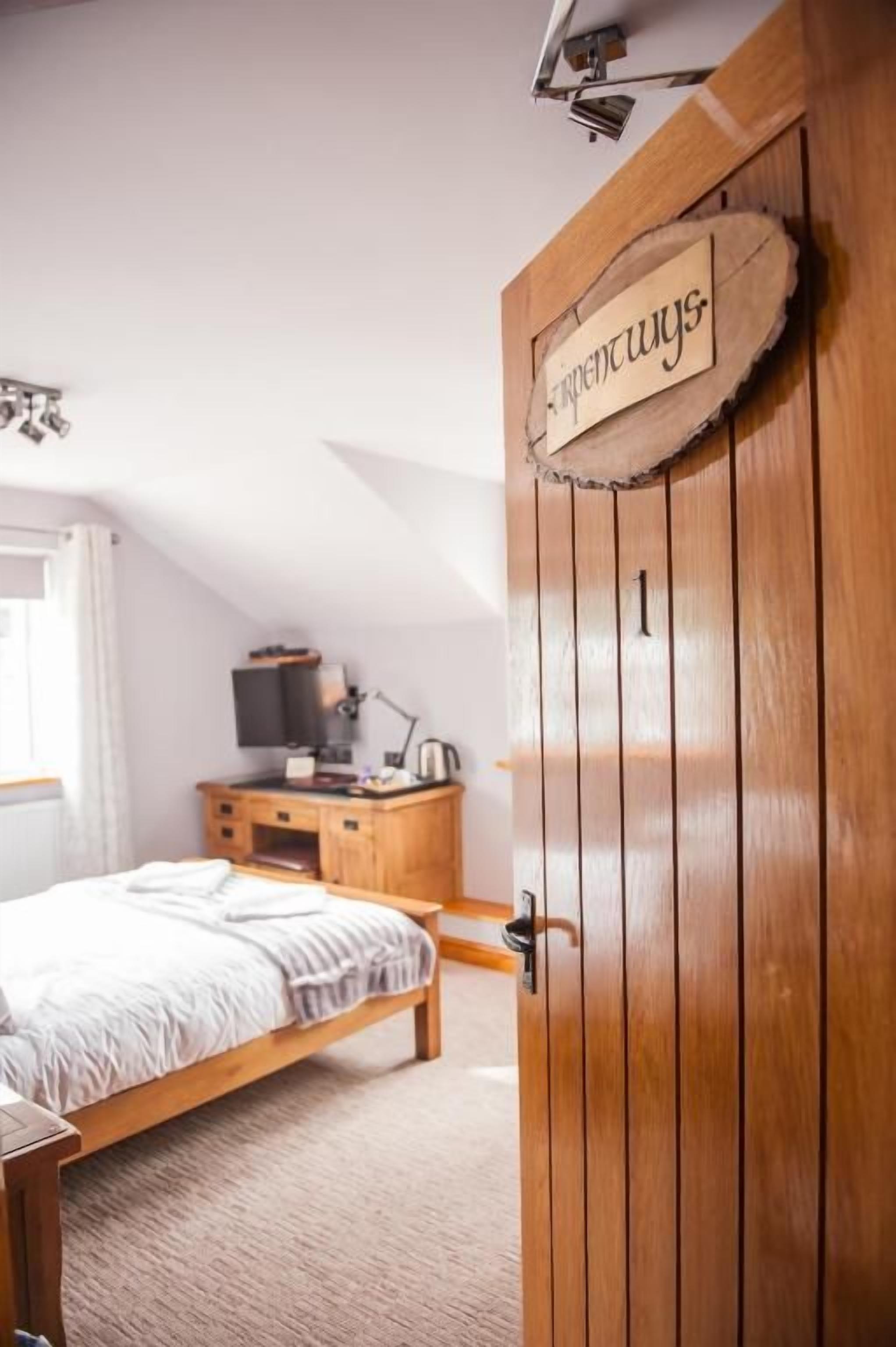 Un dormitorio con puerta de madera, una cama, una mesita de noche, un aparador y un televisor.