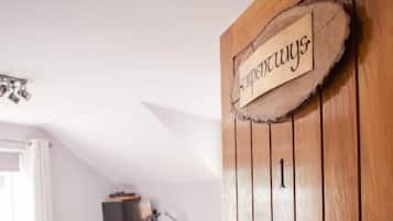 Un dormitorio con puerta de madera, una cama, una mesita de noche, un aparador y un televisor.