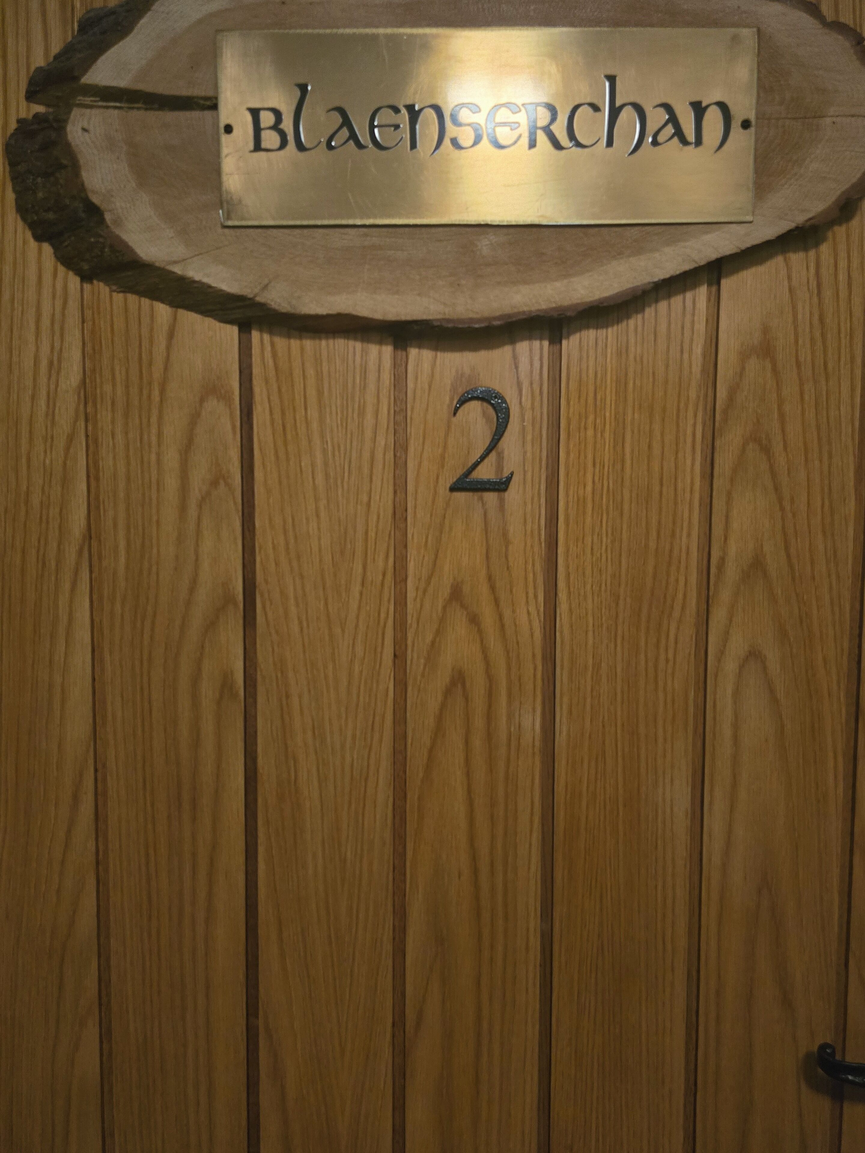 A wooden door with a metal plaque reading "Blåenscherchan" and the number "2" on it.