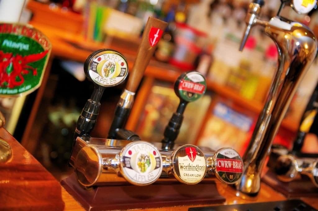 Un sistema de grifería con varias etiquetas de cerveza, incluyendo 'Taffey's Apple' y 'Worthington's Cream/Low'.