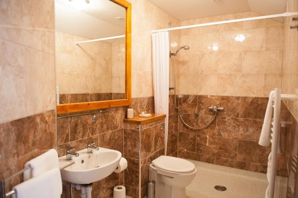 Un baño con lavamanos, inodoro, ducha y espejo.