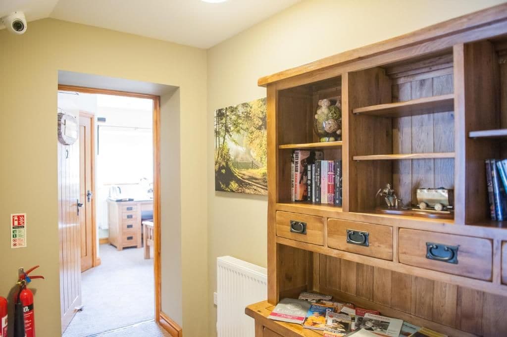 A room with a wooden cabinet, a fire extinguisher, and a painting on the wall.