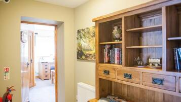 A room with a wooden cabinet, a fire extinguisher, and a painting on the wall.