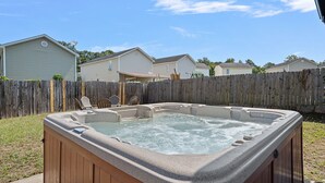A backyard with a hot tub, a wooden fence, and houses in the background.