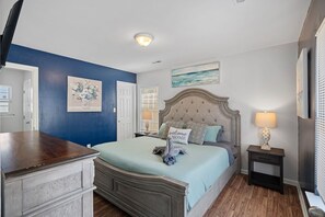 Ein Schlafzimmer mit einem Bett, Nachttischen, einer Kommode und Kunstwerken an den Wänden.