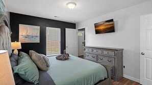 A bedroom with a bed, a dresser, a painting, and a window with blinds.