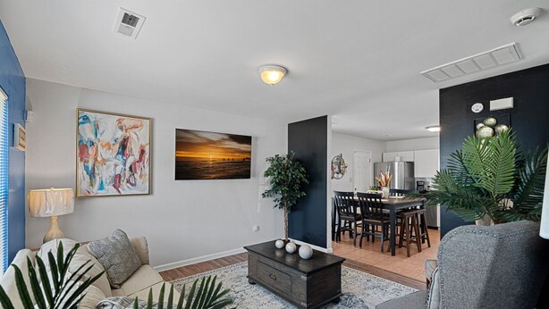 A living room with a sofa, coffee table, and a dining area with chairs and a table.