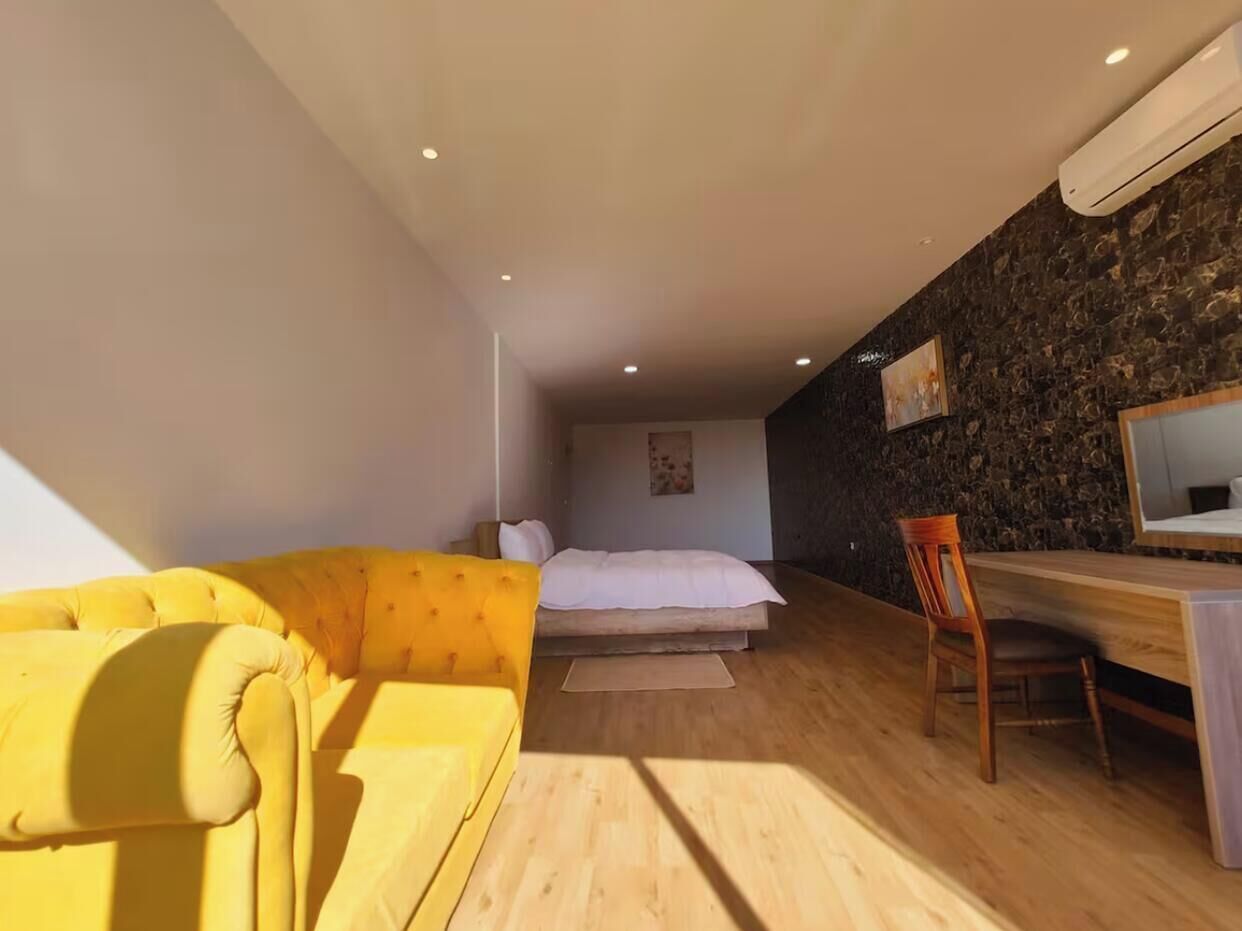 Una camera da letto con un letto, un divano giallo, una scrivania e una sedia.