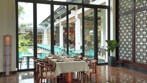 A restaurant with a glass wall offering a view of outdoor seating and a decorative screen.