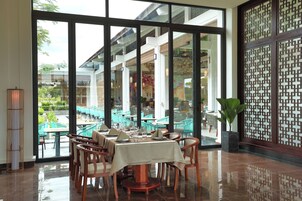 Un restaurante con pared de vidrio que ofrece vistas de mesas al aire libre y una pantalla decorativa.
