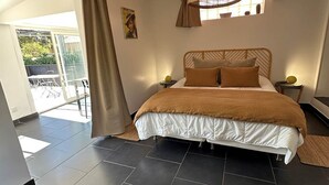 Un dormitorio con una cama grande, una lámpara colgante, una ventana con cortinas y vistas al exterior.