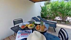 An outdoor dining area with a table set for breakfast, including fruits and a newspaper. - 1. Appart N°2 - HOME CASSIS - House Les Calanques (CASSIS)