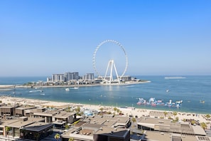 A coastal cityscape with a prominent white Ferris wheel, beachfront, and modern buildings.