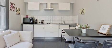 A modern kitchen with white cabinets, a black countertop, and a dining area with a table and chairs.