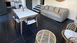 Un espai modern d'estar amb zona de menjador, sofà i cadires de vimetla.
