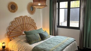 Un dormitori amb un llit, una làmpada de nit, una finestra amb cortines i decoració a la paret.