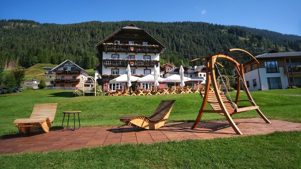 Un hotel con un edificio grande, zona de estar al aire libre y un columpio.