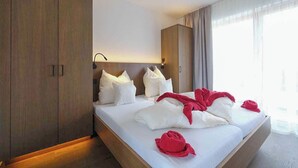 Una habitación de hotel con una cama grande, un armario de madera y una mesita de noche con lámpara.