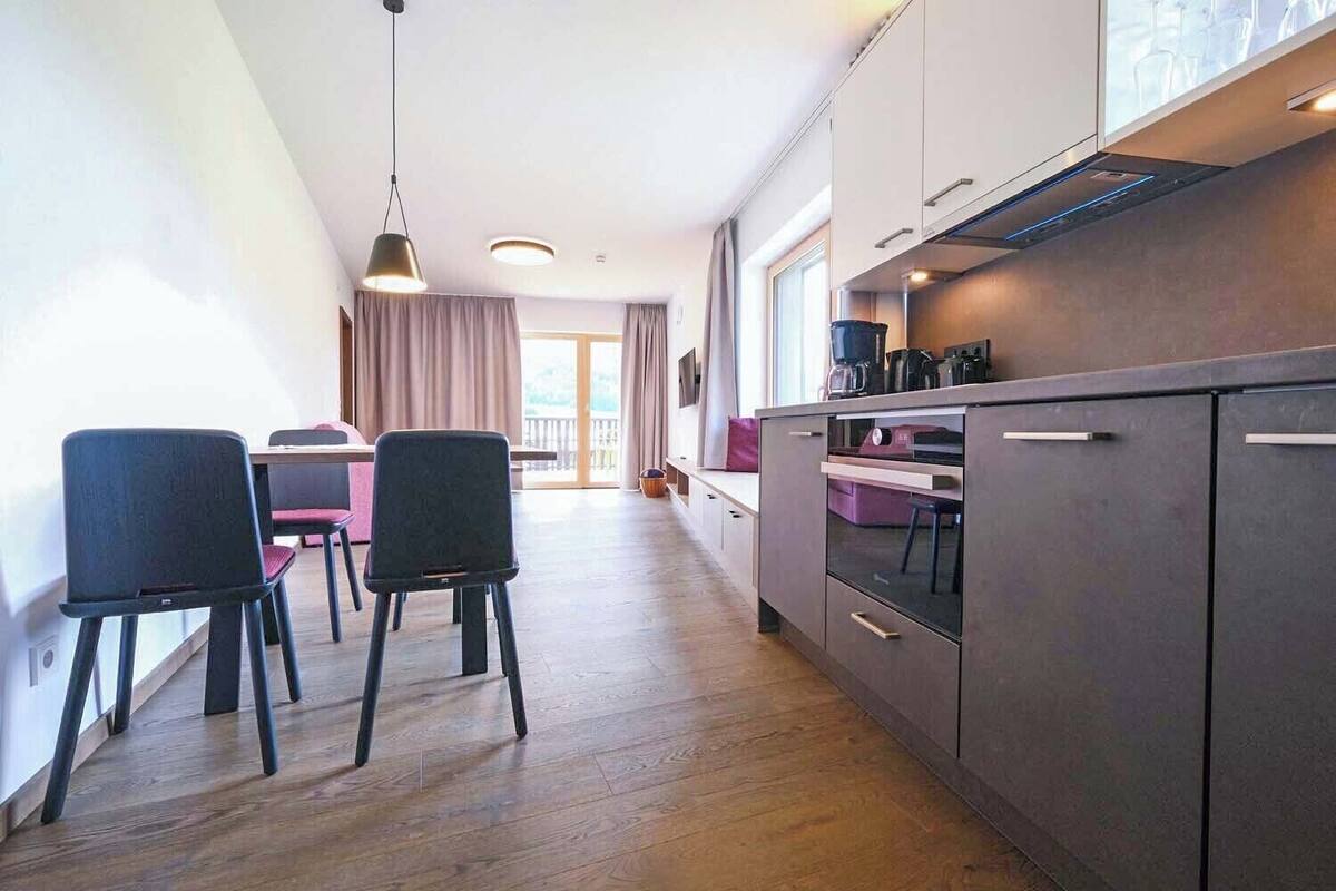 Una cocina moderna con comedor, piso de madera y vistas al exterior.